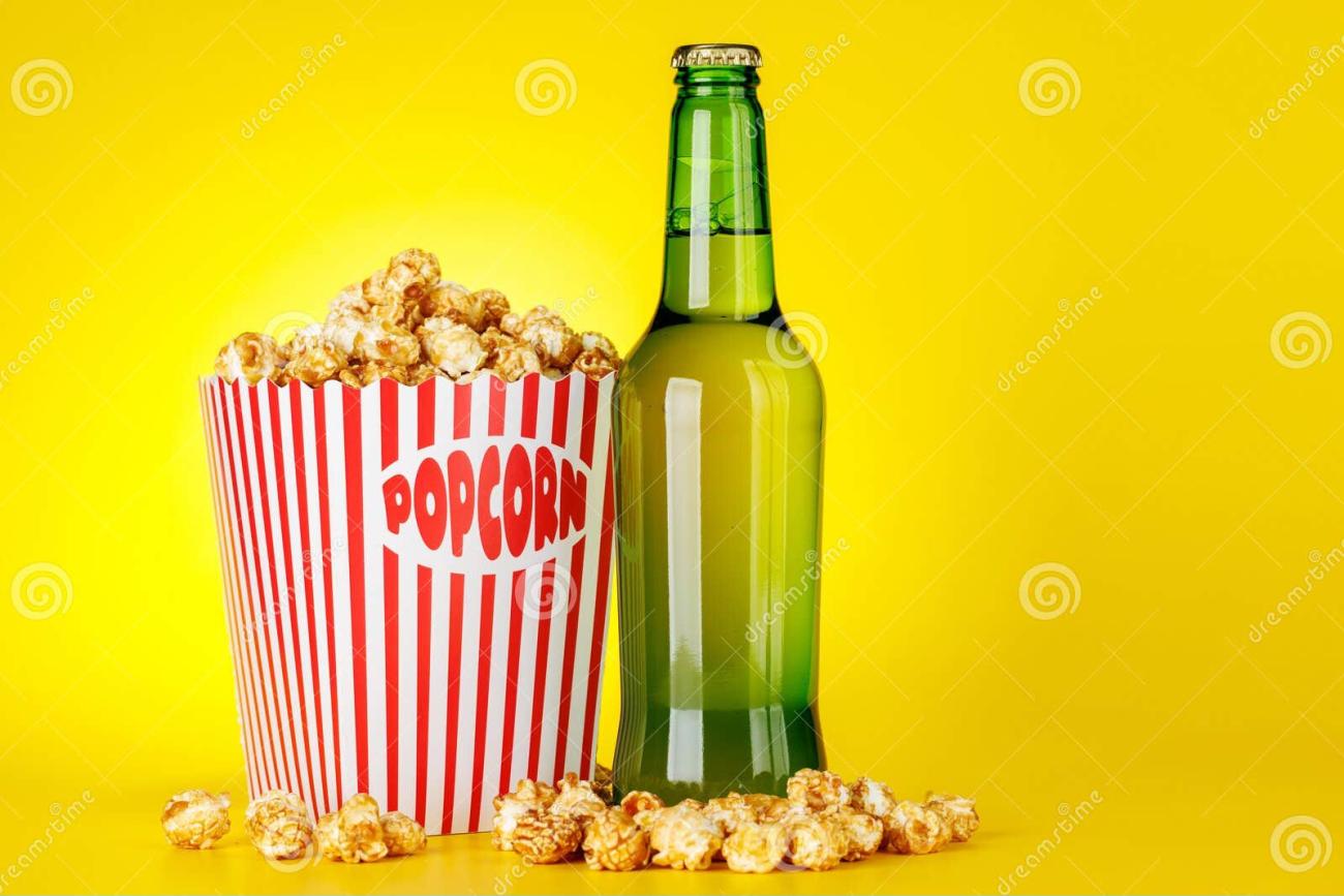 Bucket of popcorn and bottle of beer on an amber background